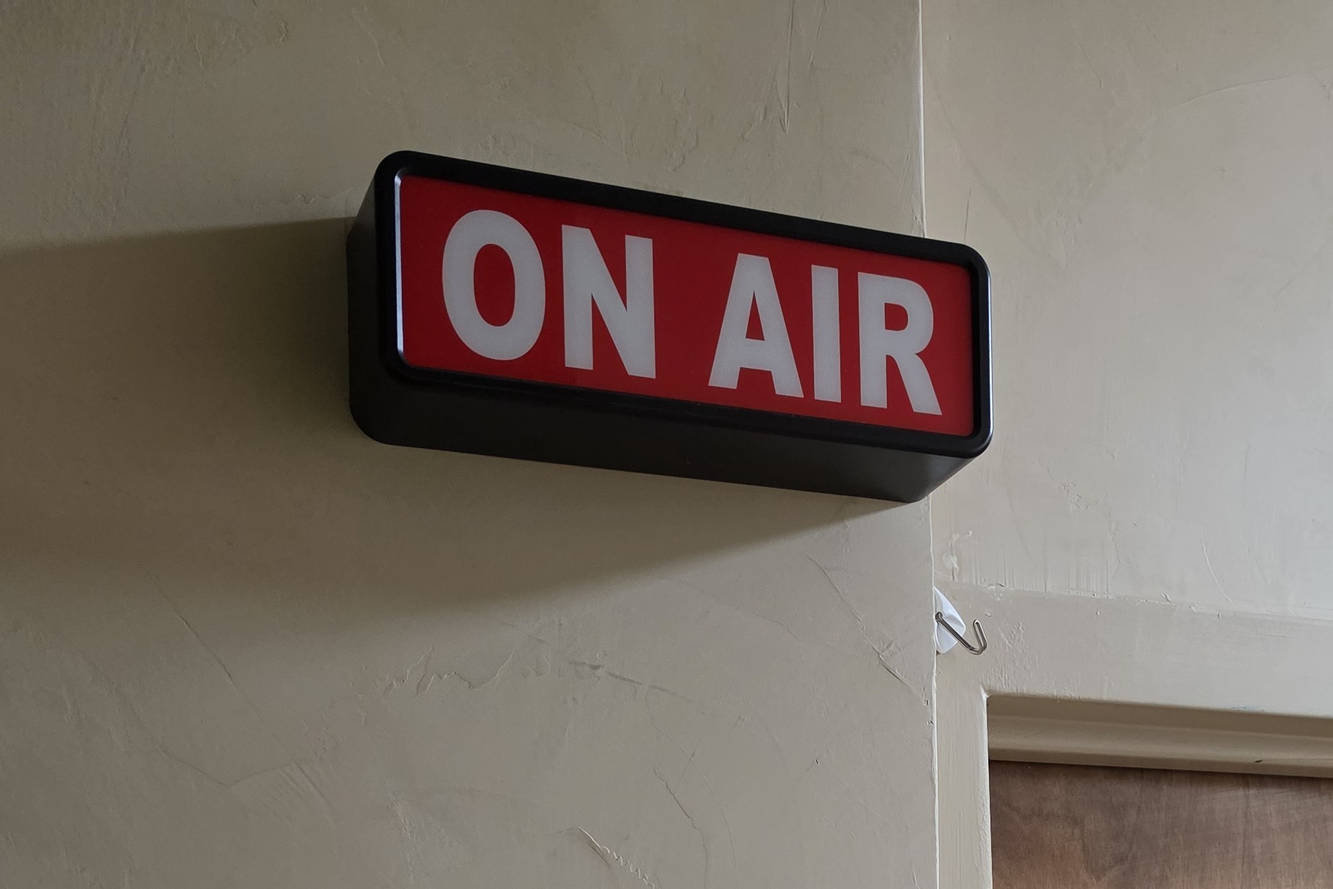 Studio door with the ON AIR sign and Red Quill Media plaque