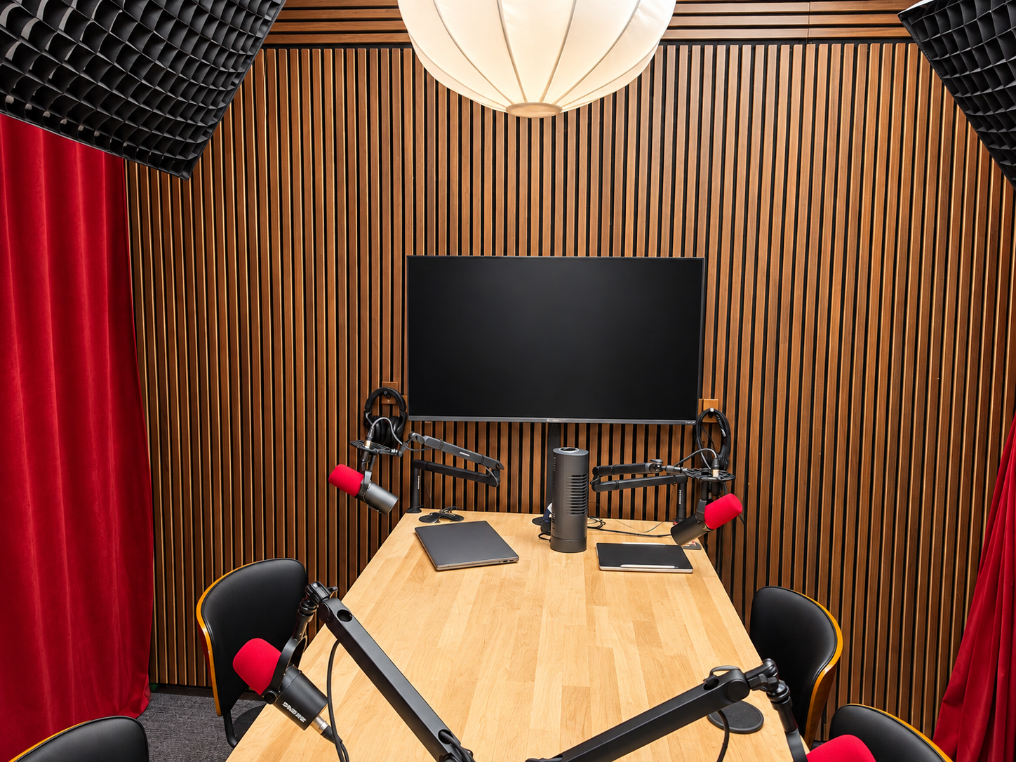 Podcast table setup with dual mic arms, monitor, and studio lighting
